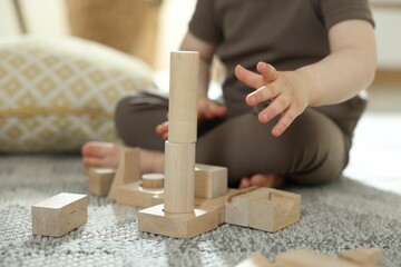 Cute little child playing with wooden building blocks at home, closeup