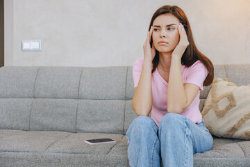 Obraz premium Young Woman Suffering From Headache While Sitting on Sofa at Home