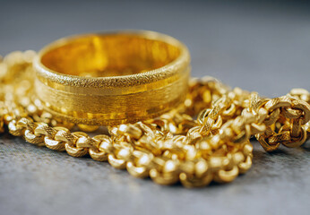 Gold price, gold jewelry, close-up of gold ring and gold necklace on grey background.