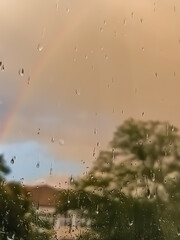 Defocused background of sky at sunset with yellow clouds and rainbow, raindrops in the foreground. Backdrop, copy space, photo overlay, spring, summer, fall