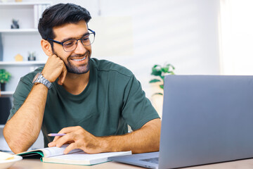 Man enjoying a productive work session from modern living space. Young man working at home. Home office., freelance. Focused handsome freelancer doing online research over laptop.