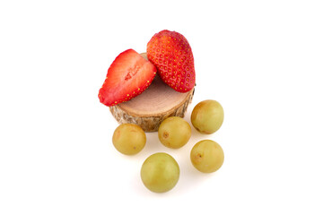 strawberries and green grapes are arranged atop a wooden slice. This minimalist arrangement on a...