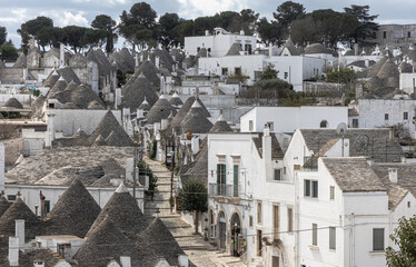 Traditional Street in Alberobello with Multiple Trulli Houses and Clear Blue Sky in Puglia, Italy