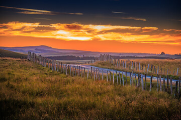 Evening landscape on the Aubrac mountains.
Field and hills on a beautiful spring evening in central France, with rock and stone walls.
