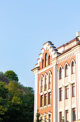 Brick and white modern building facade with tall windows and decorative arches against blue sky.
