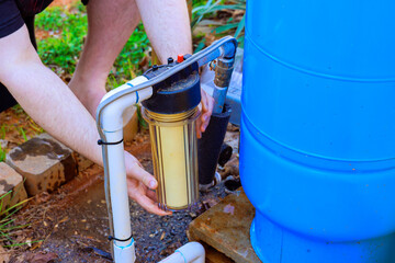 Person is changing yellow filter in water filtration system in backyard