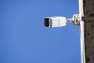White CCTV camera on top of the building. Secret recording of what is happening. Modern technology and equipment for security around.