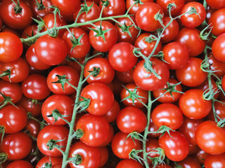 Horizontal photo of small red cherry tomatoes. Against the background of ripe vegetables. Healthy food, organic food market, fresh juicy tomatoes.