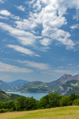 Fototapeta premium Serre Poncon Lake gleaming under cloudy sky in Hautes Alpes, Provence Alpes Cote d'Azur, France