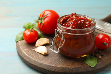 Tasty sun dried tomatoes, fresh vegetables and peppercorns on light blue wooden table, closeup