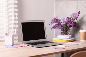 Fototapeta premium Workplace with laptop and beautiful flowers in office