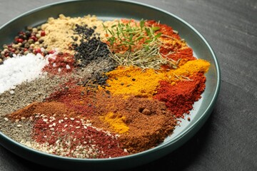 Different aromatic spices on dark textured table, closeup