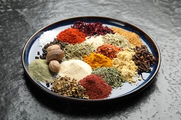 Different aromatic spices on dark textured table, closeup