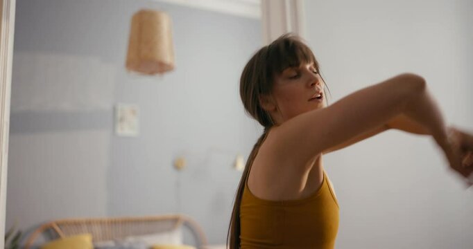 Cheerful girl in yellow top dances afro dance and improvises at home in modern apartment. Cheerful girl dancing improvised modern dance