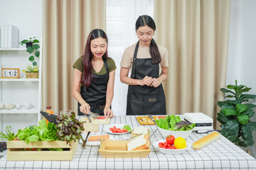 Two asian woman study online in the classroom making sandwich together in the home kitchen. Homemade and Learn online concept
