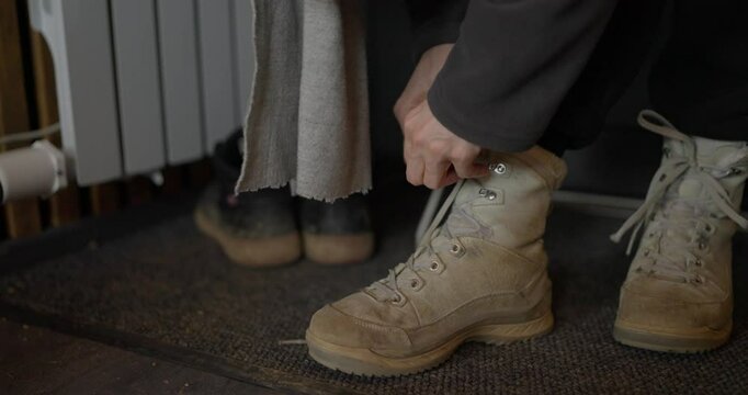 Close up person ties his hiking boots before leaving home. Tying laces and wearing shoes for a hiking trip outside the city