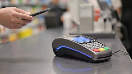 Person uses smartphone for wireless payment at modern point of sale terminal - Powered by Adobe