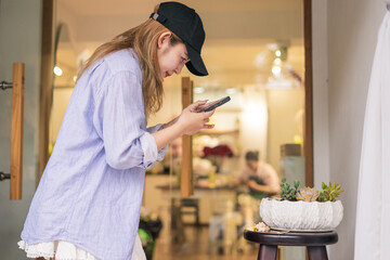Focused woman taking a smartphone picture of potted succulents in a shop during daytime activities