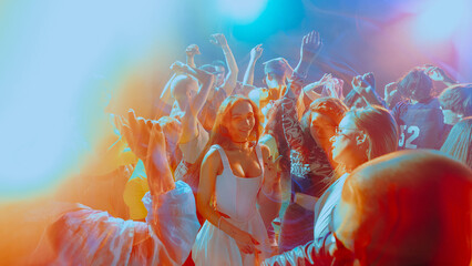 Vibrant party scene with people dancing under colorful lights. Concept of nightlife, party, youth, summer, festivity, celebration