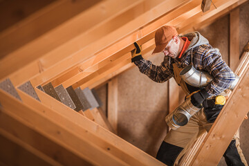Skilled Worker Navigating Wooden Beams During Construction in a Residential Attic