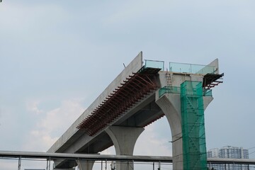 Fototapeta premium Concrete flyover under construction with exposed steel reinforcements and green safety netting