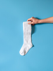 Hand is holding cotton white golf socks flat lay. Clothing production, sewing workshop
