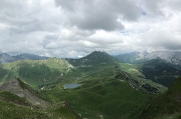Panoramic view of lush green valley with mountains under a cloudy sky