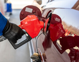 A man fills up a big red car