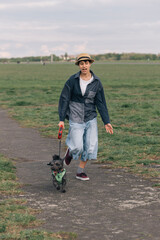 Teenager girl walking with black dog in park during outdoor activity