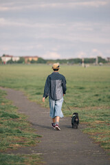 Teenager girl walking a small black dog in a park during a cloudy day