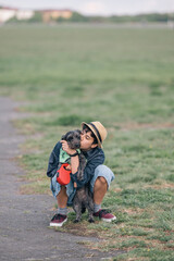Young girl crouching and kissing her dog in a park