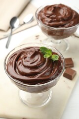 Delicious chocolate pudding in dessert bowls on white table, closeup