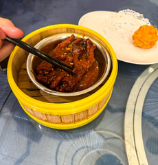 Close-up of chicken feet dim sum, also called phoenix claws, served in a bamboo steamer. A traditional Cantonese dish stewed in flavorful sauce, commonly enjoyed at dim sum restaurants.

