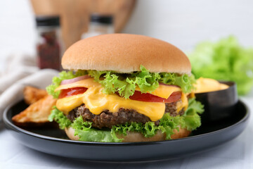 Tasty cheeseburger with sauce on white table, closeup