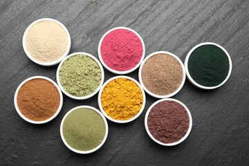 Different superfood powders on black table, flat lay