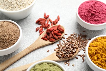 Different superfood powders on light grey table, closeup