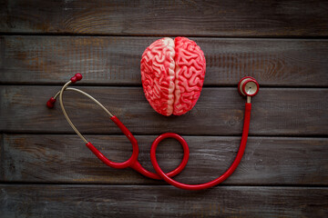Human brain anatomical model with red stethoscope, top view. Mental health concept.