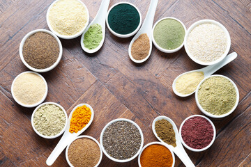 Frame of different superfood powders in bowls and spoons on wooden table, flat lay. Space for text