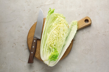 Cut Chinese cabbage and knife on light grey table, top view