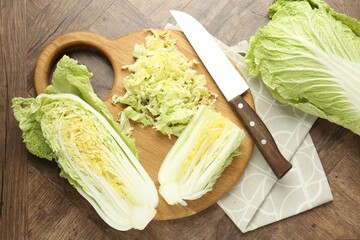 Fresh Chinese cabbages and knife on wooden table, flat lay