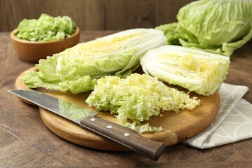 Fresh Chinese cabbages and knife on wooden table, closeup
