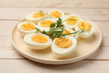 Boiled eggs and microgreens on wooden table, closeup