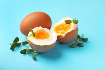 Soft boiled eggs with microgreens on light blue background, closeup