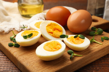 Halves of hard boiled eggs with microgreens on wooden table, closeup