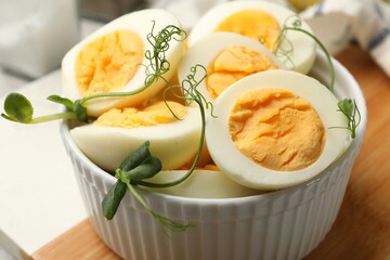 Hard boiled eggs with microgreens on grey table, closeup
