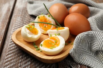 Soft boiled eggs with green onions on wooden table, closeup