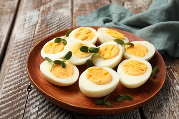 Hard boiled eggs with microgreens on wooden table, closeup