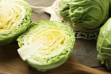 Fresh cabbages and net bag on wooden table, closeup