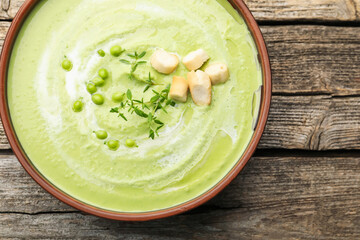 Tasty pea cream soup with croutons and thyme on wooden table, top view