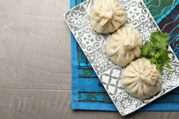 Delicious khinkali served with cilantro on grey table, top view. Space for text